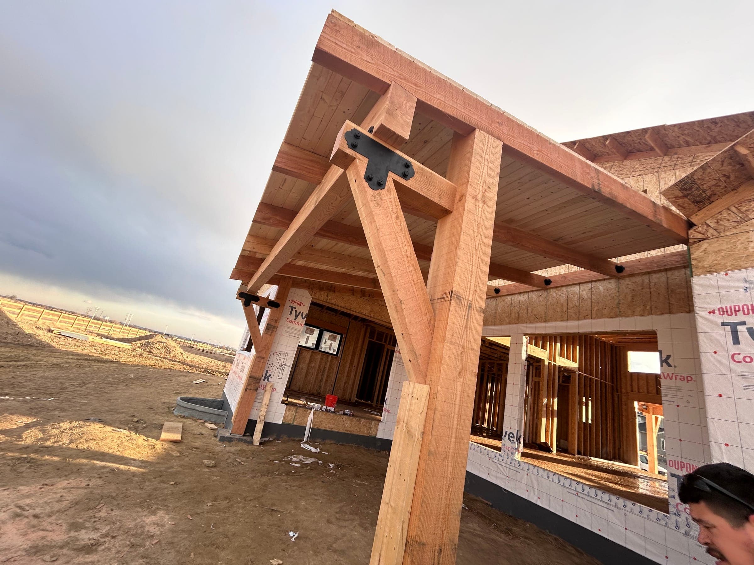 Heavy timber porch frame with steel bracket joinery, mid-construction