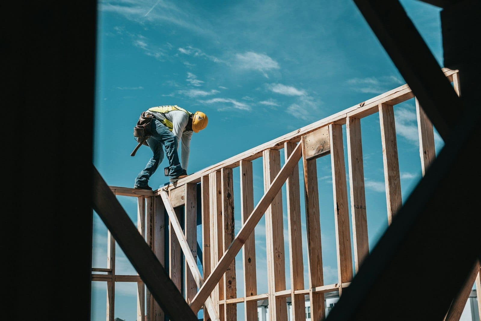 Framer raising a stud wall against a blue sky