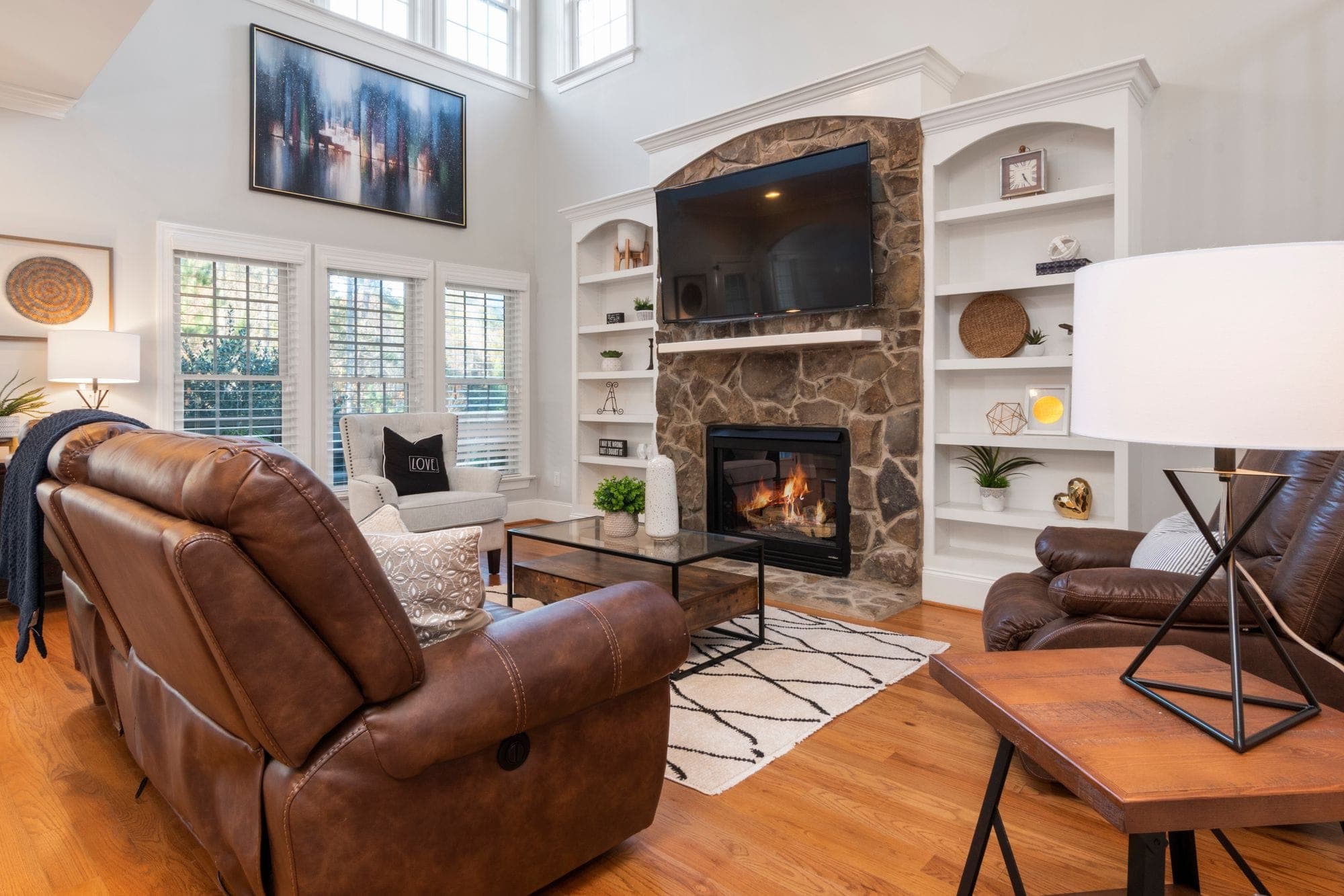 Renovated living room with a stone fireplace and wood floors