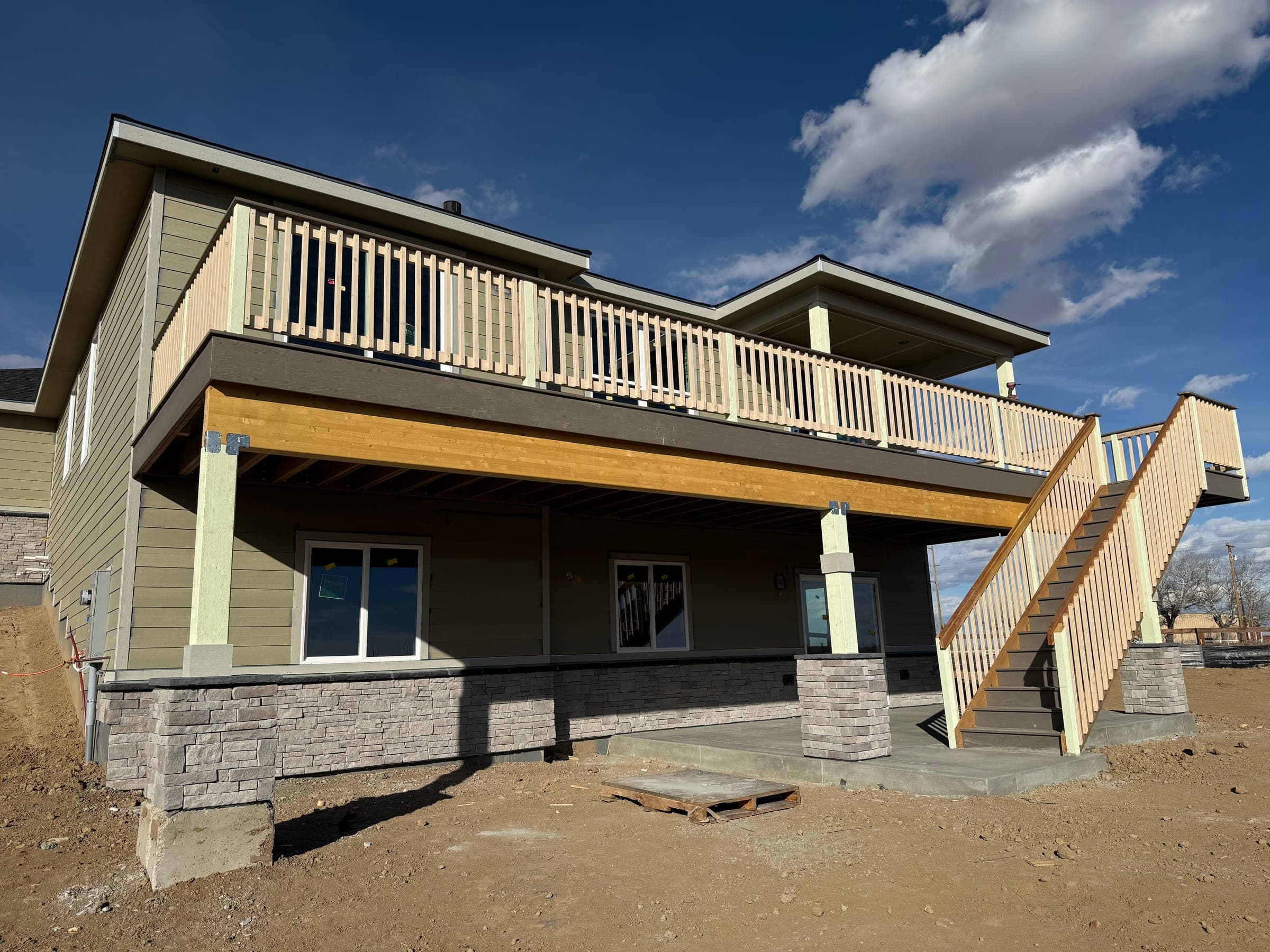 Two-story home with a full-width second-story deck and custom staircase built by Skyview Construction
